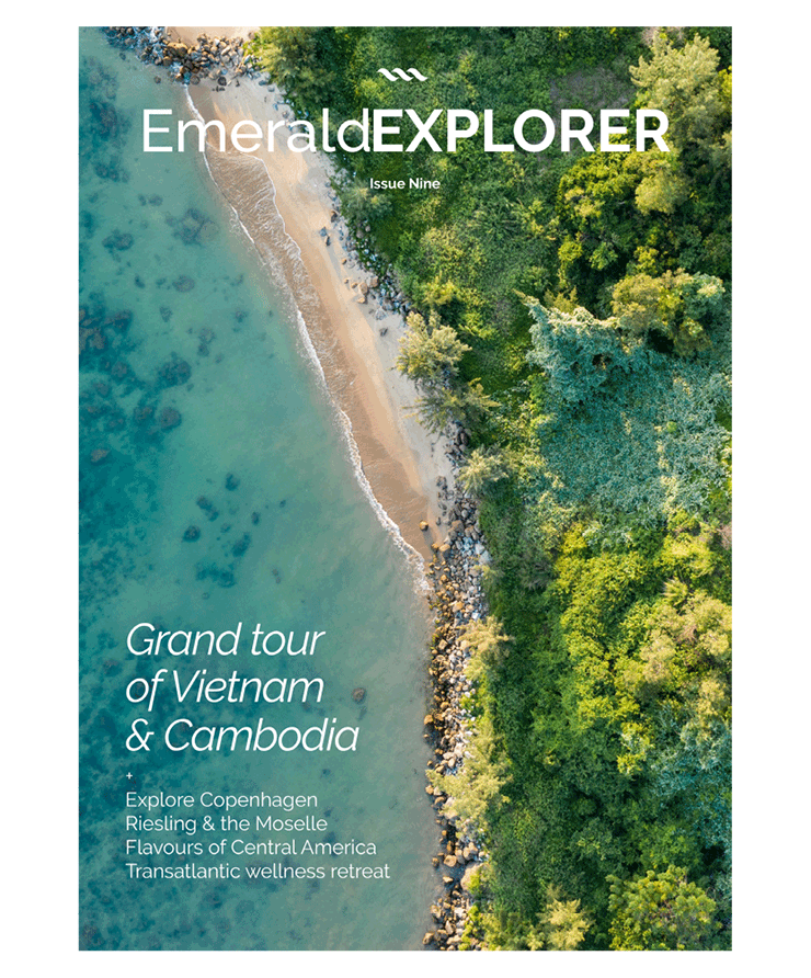  Magazine cover, with an aerial shot of the beach near a forest, with the calm blue waters 