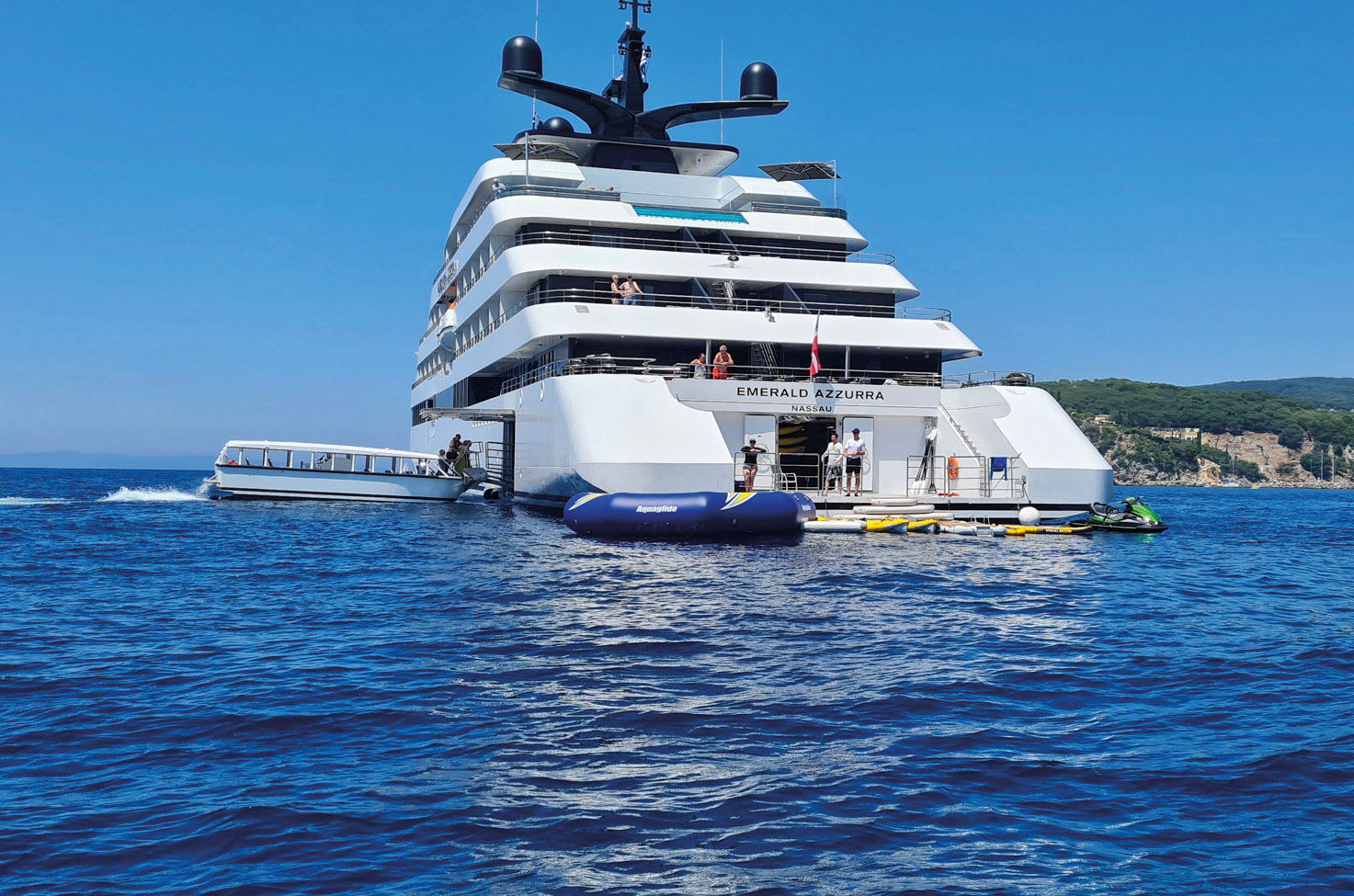 Rear of luxury yacht, where staff are setting up marina toys from the platform on the deep blue sea on a sunny, cloudless day