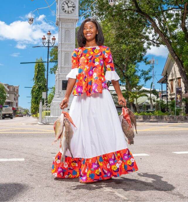 Woman in traditional clothing holding fresh fish in Seychelles