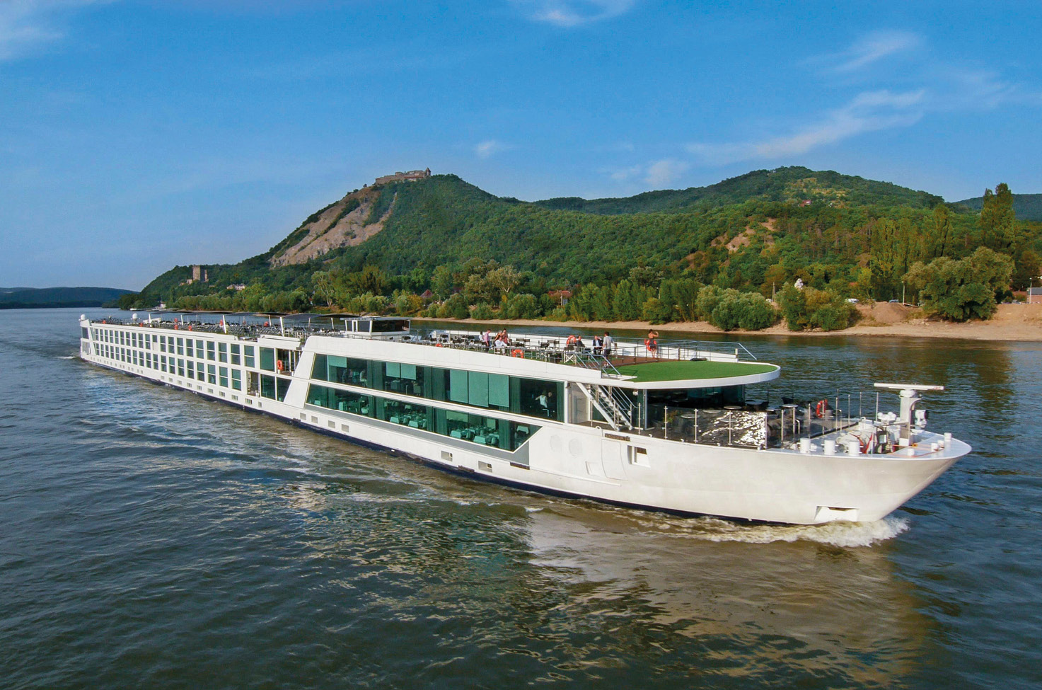 A close up image of a river cruise ship sailing along a European river