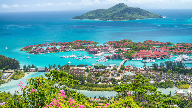 An oceanside city on Praslin Island, Seychelles, with green plants and a deep blue sea