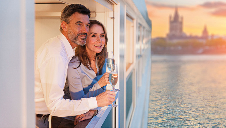 Couple enjoying a glass of Champagne whilst admiring the sunset view on board a luxury river ship  