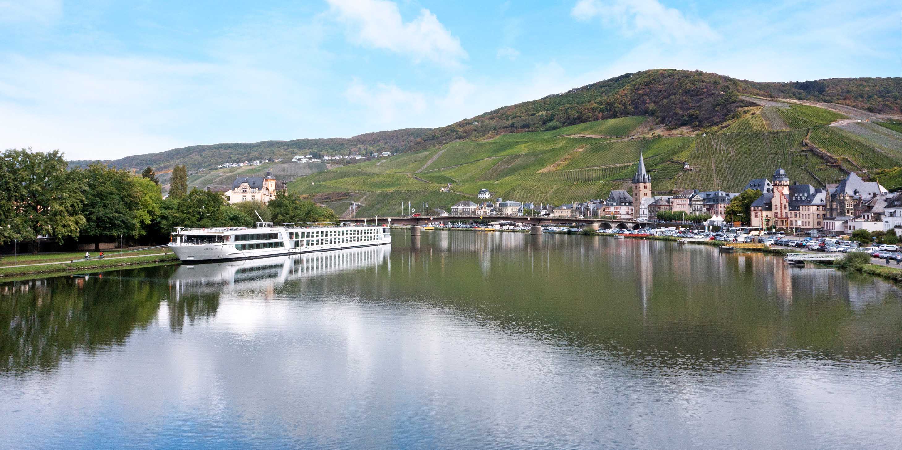 Luxury river ship docked in Bernkastel, Germany, with the landscape reflected in the water