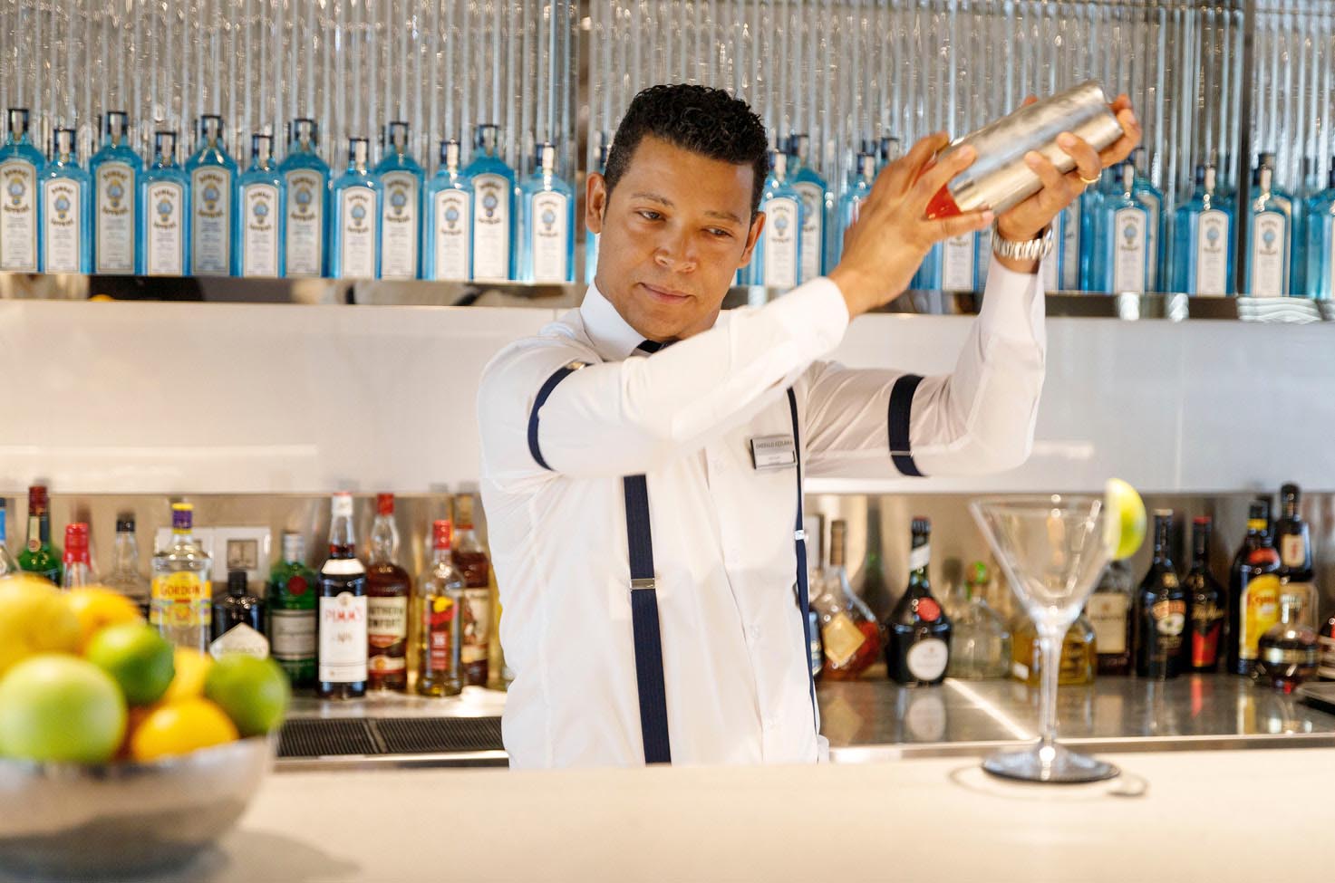 Waiter shaking up a cocktail in a mixer for a guest at the well-stocked bar of an Emerald Cruises luxury yacht cruise 