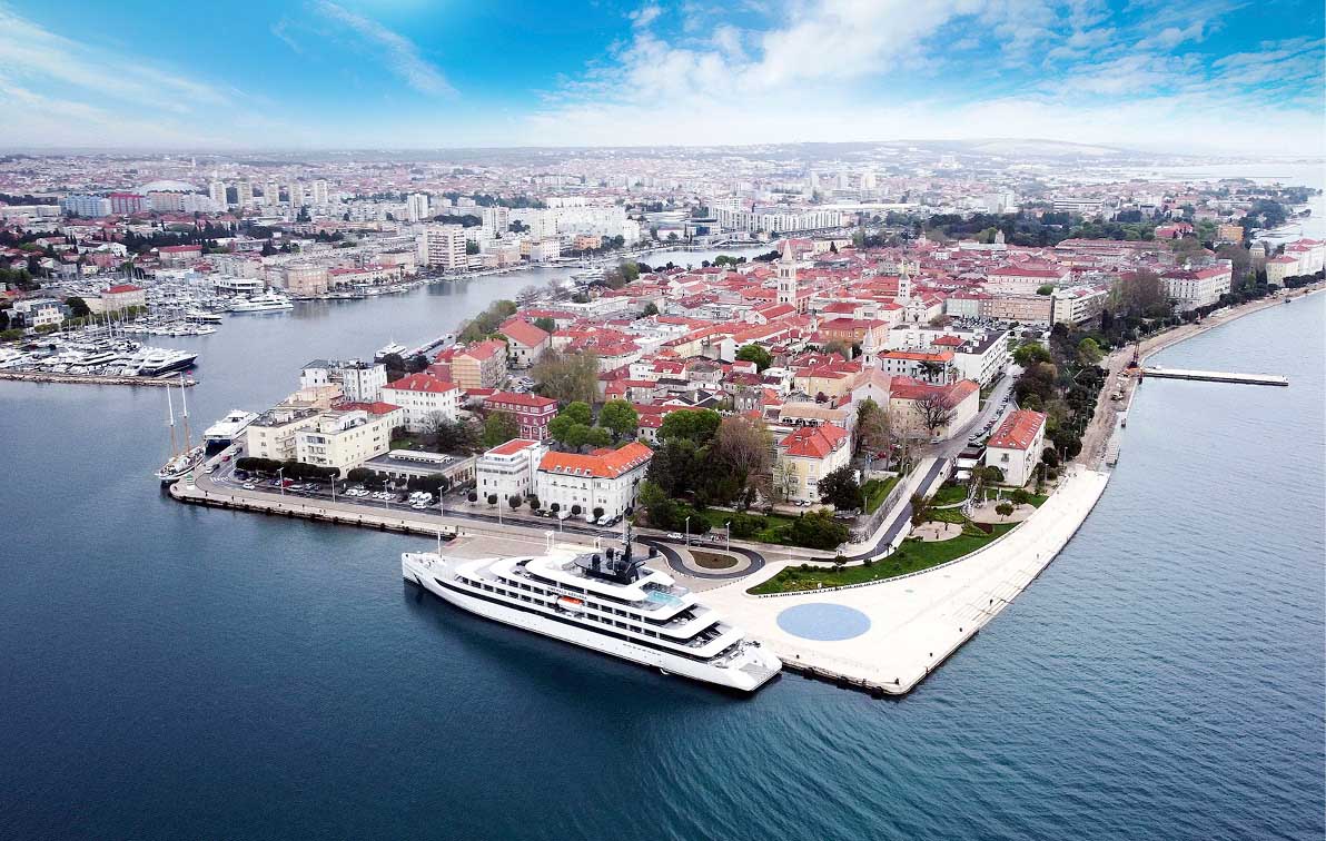 A luxury yacht is docked in a harbour close to a Croatian town