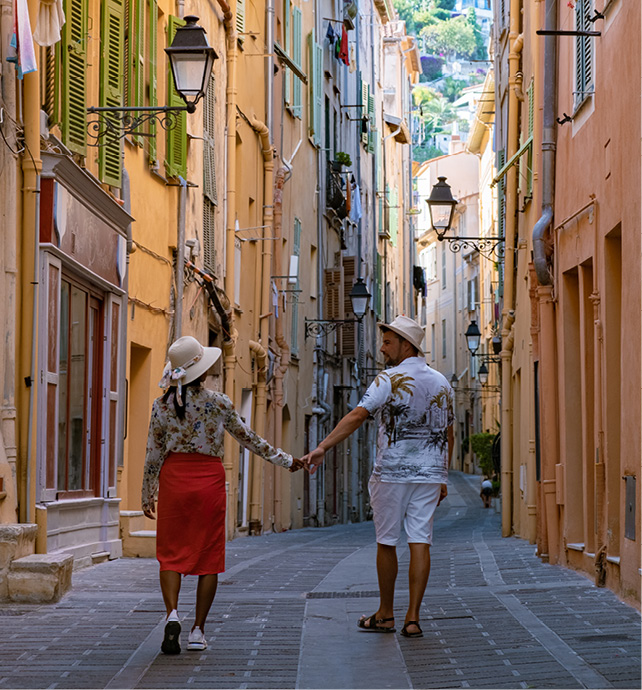 Couple holding hands walking through an old street in Menton during Summer
