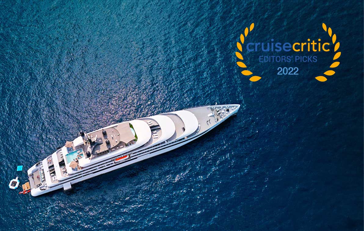 A luxury yacht sails on a dark blue sea, seen from a bird’s-eye view